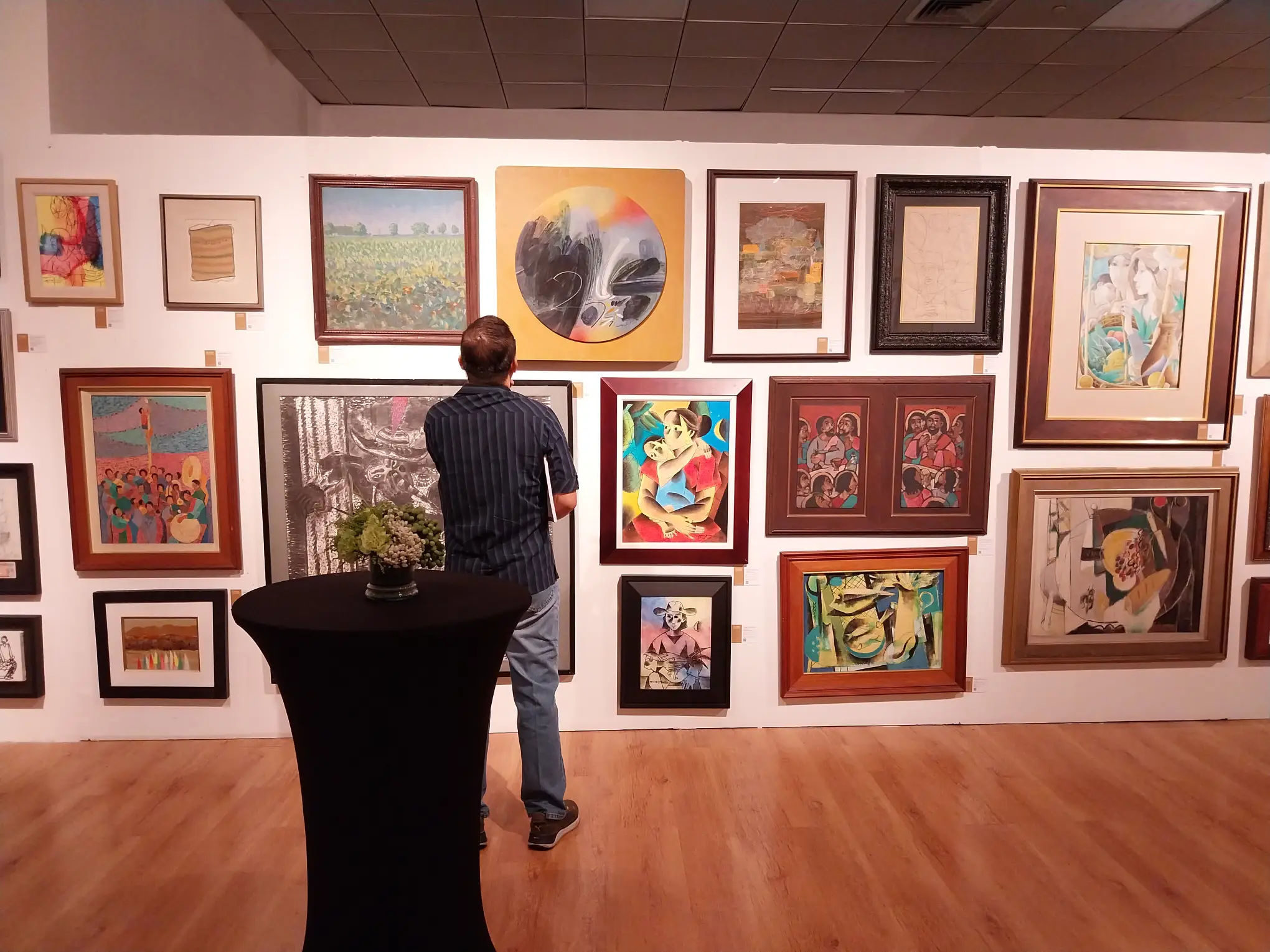 A person looking at some of the paintings for sale at "Finer Pursuits" in Salcedo Auctions.