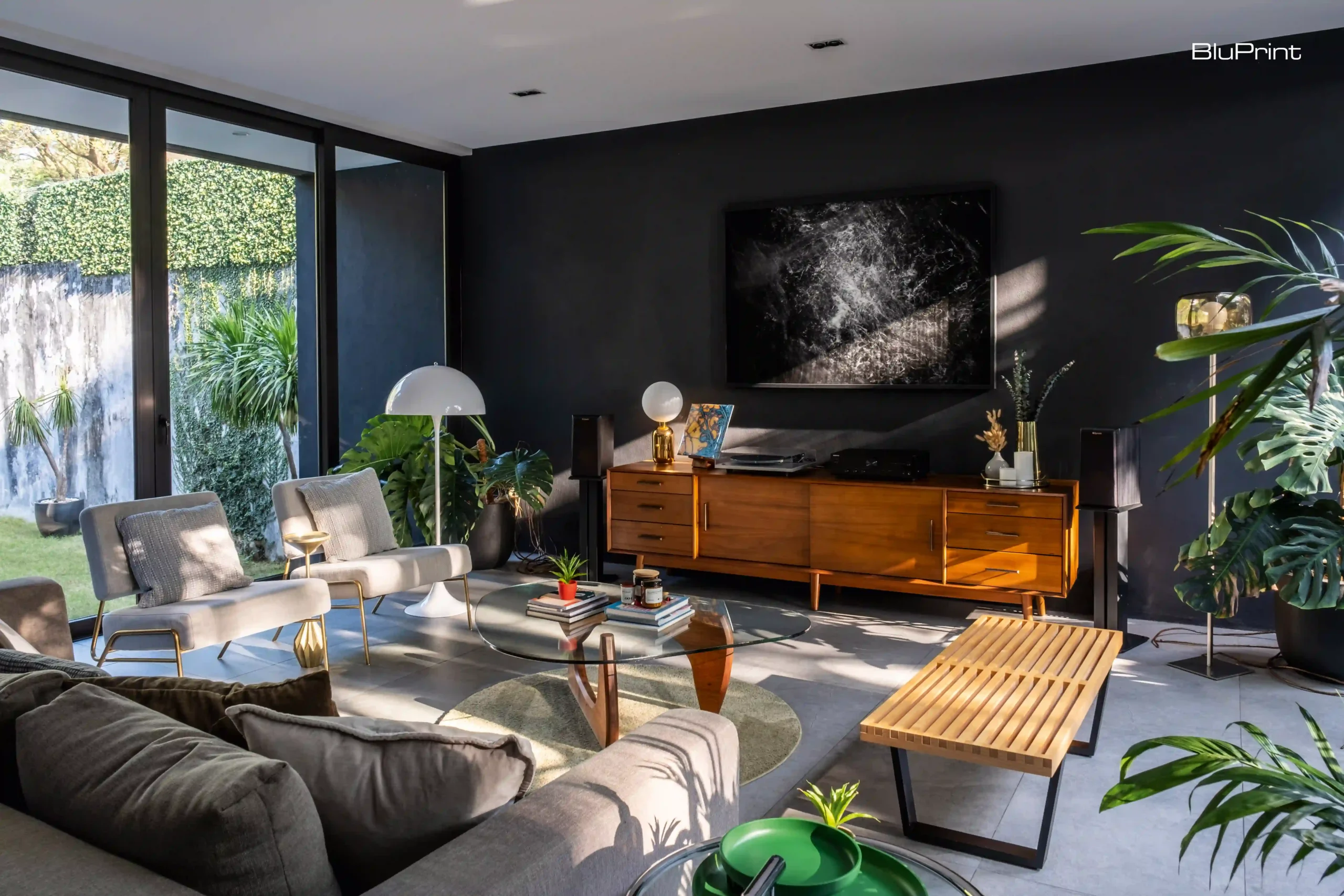 No excess, no distractions. Just a well-curated mix of furniture, framed photography, and expansive glass panels that frame the driveway on one side and the backyard on the other. The absence of a TV is intentional, with nature providing all the movement and change the space needs.