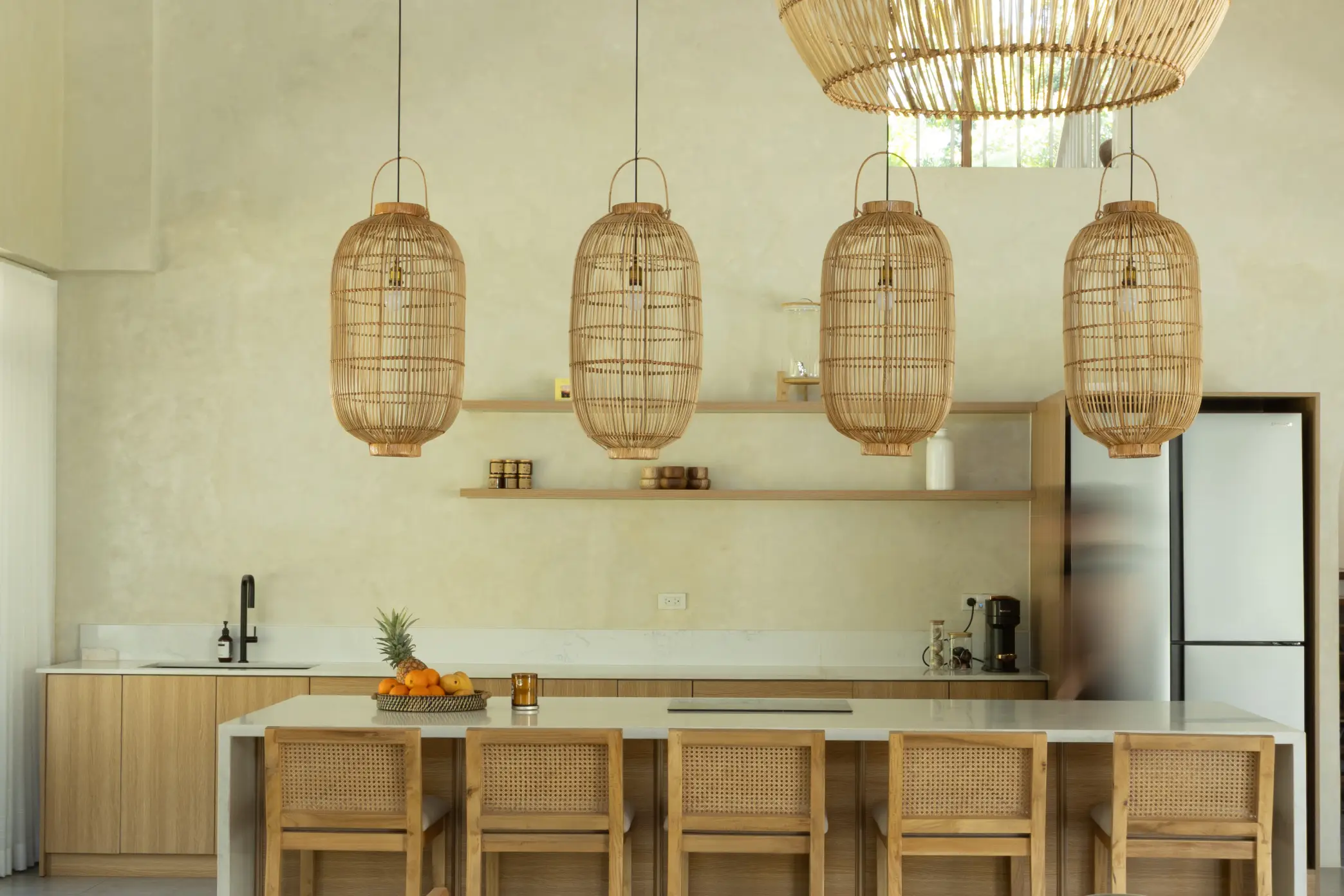 Rattan pendant lamps and solihiya-back chairs add a warm, tropical touch to the kitchen and offset the coldness of the granite countertops.