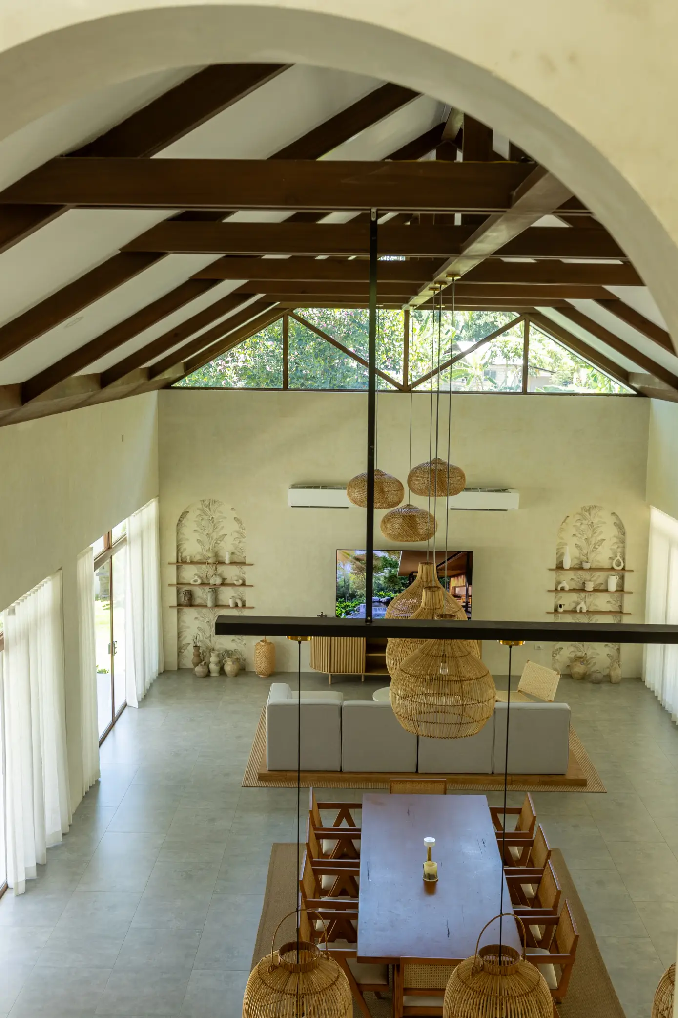 An arched wall on the upper floor frames a view of the open-plan spaces below, highlighting the home’s vertical expanse.