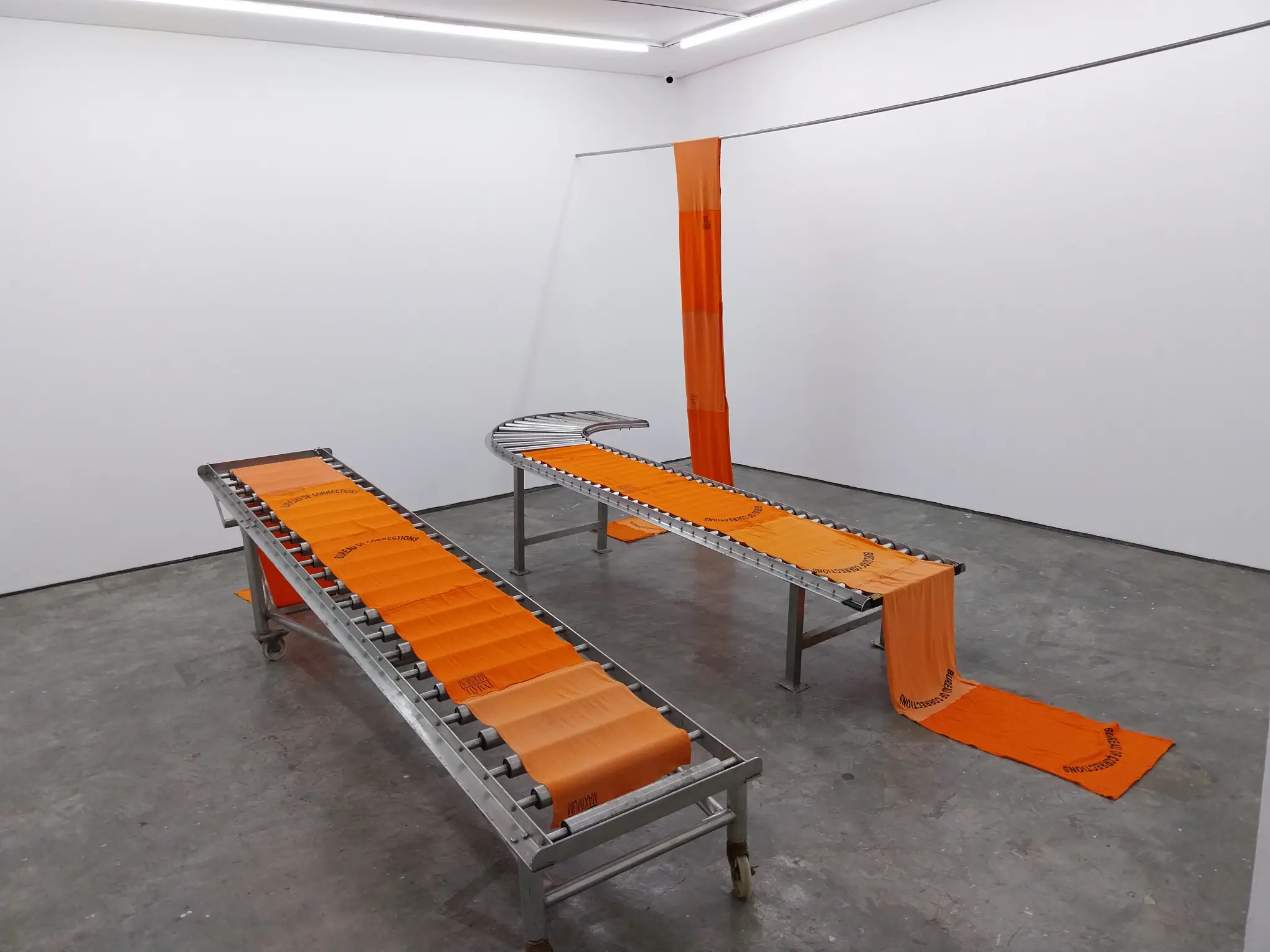 A conveyor belt of prison attire shown at Vien Valencia's "Perimeters" at Artinformal Gallery.