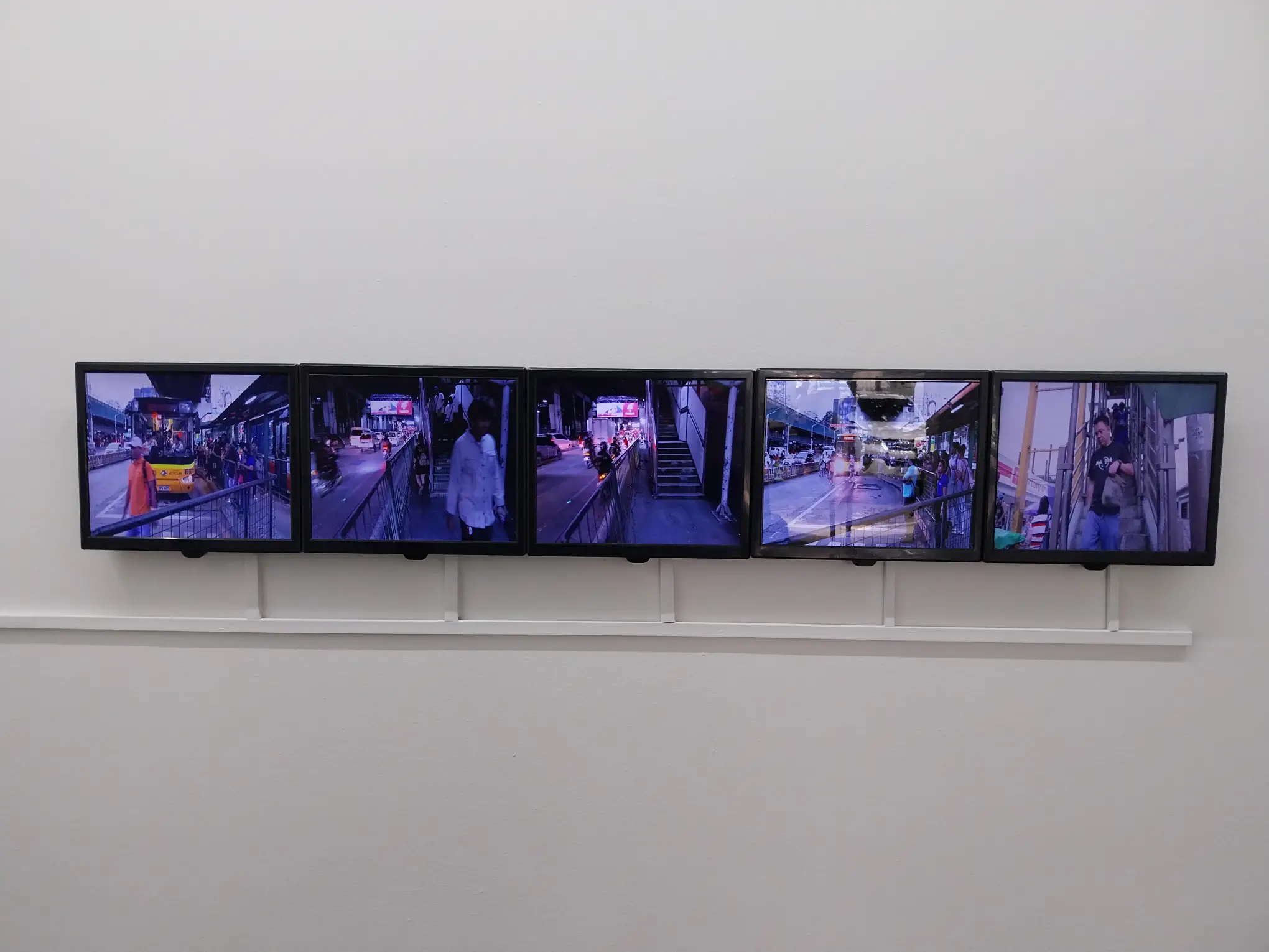 Television screens showing different commuters in motion.