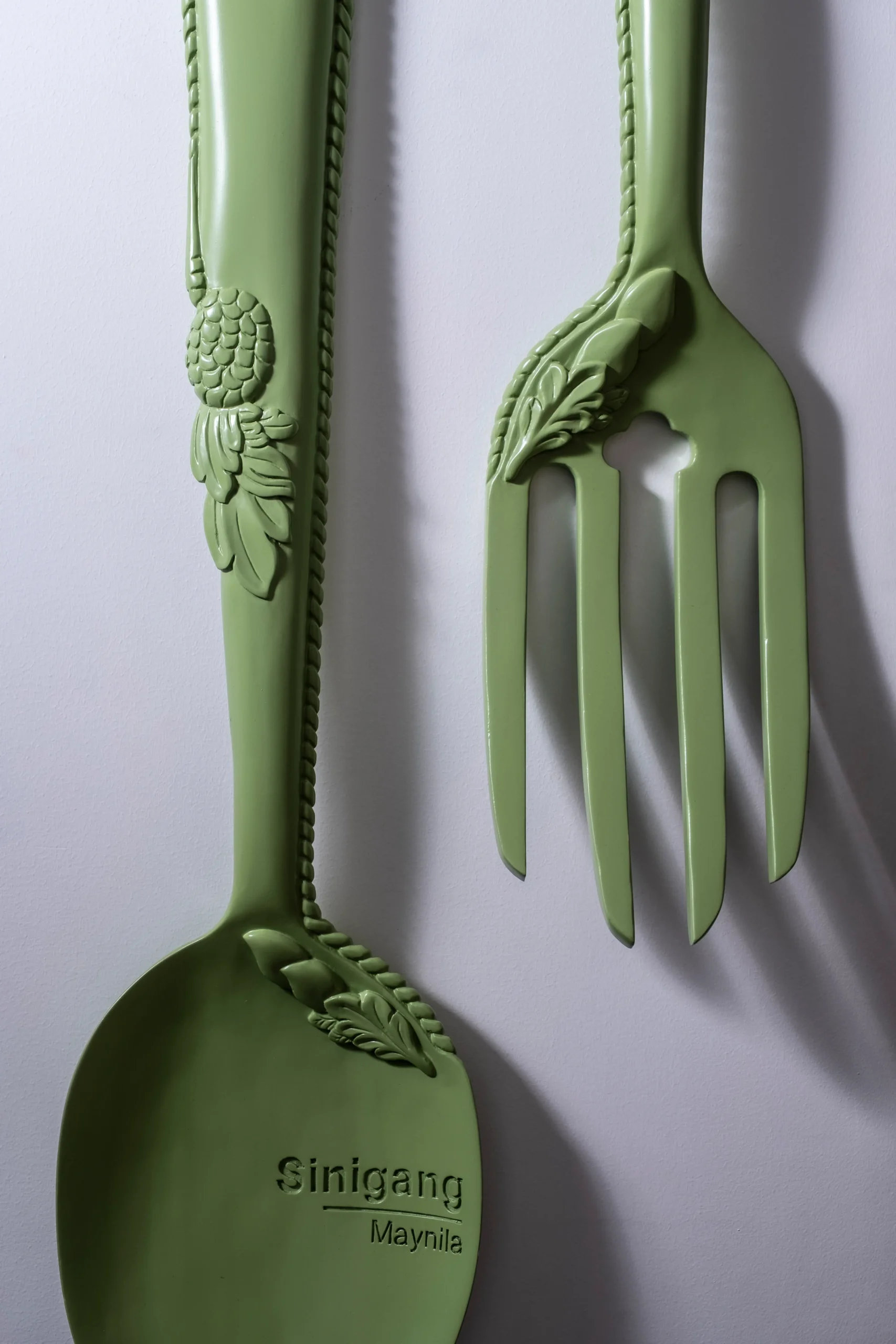 Oversized green Kubyertos spoon and fork by Ito Kish in Makati showroom, engraved “Sinigang Maynila.”