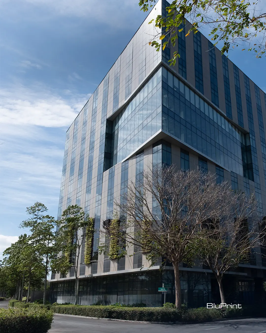 LHK Building in Nuvali, a modern glass and steel office structure with vertical fins and landscaped greenery along its facade.