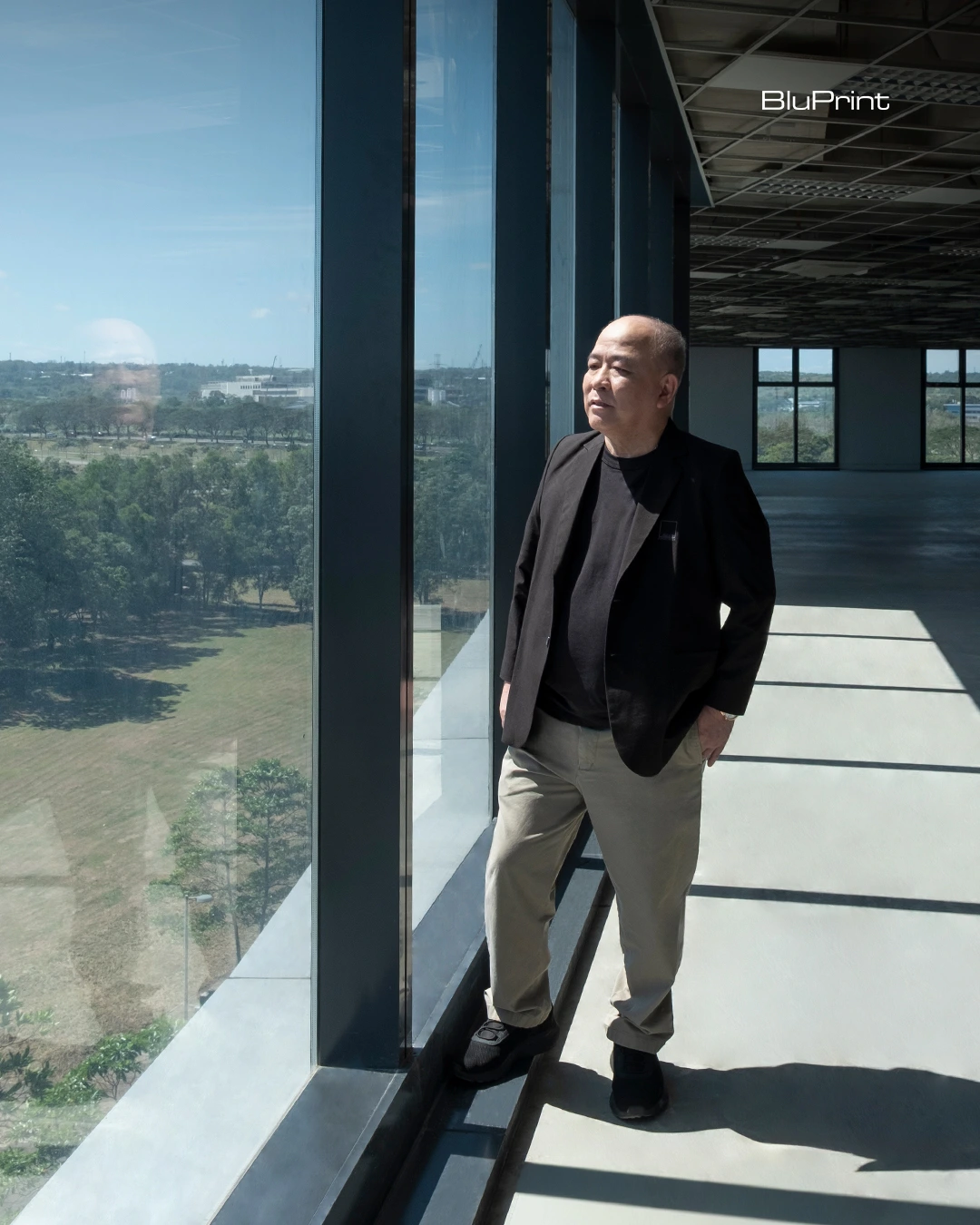 Jose Siao Ling of JSLA Architects standing inside the LHK Building in Nuvali beside floor-to-ceiling glass windows.
