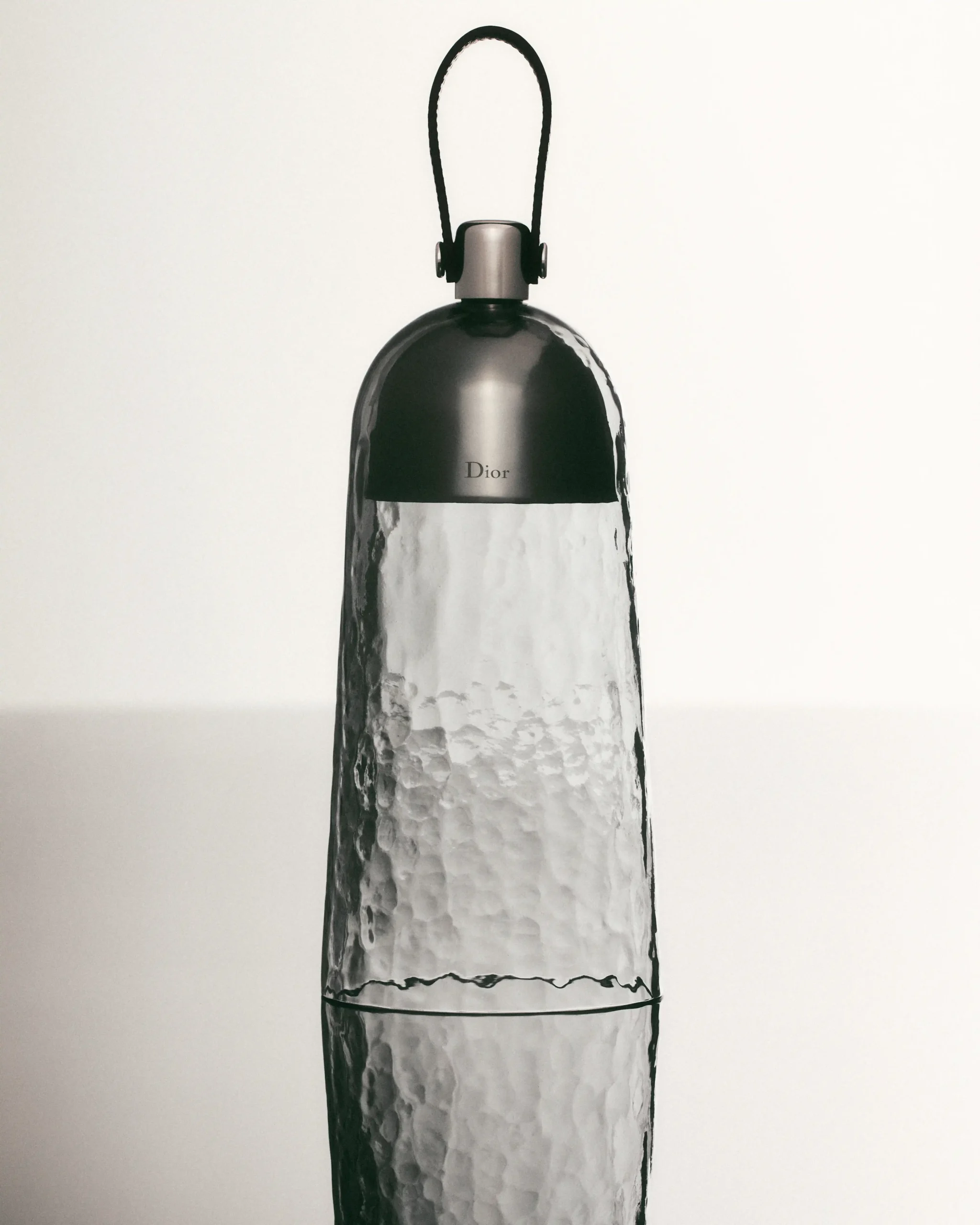 Dior perfume bottle with a rounded top and a black loop cap against a light background.