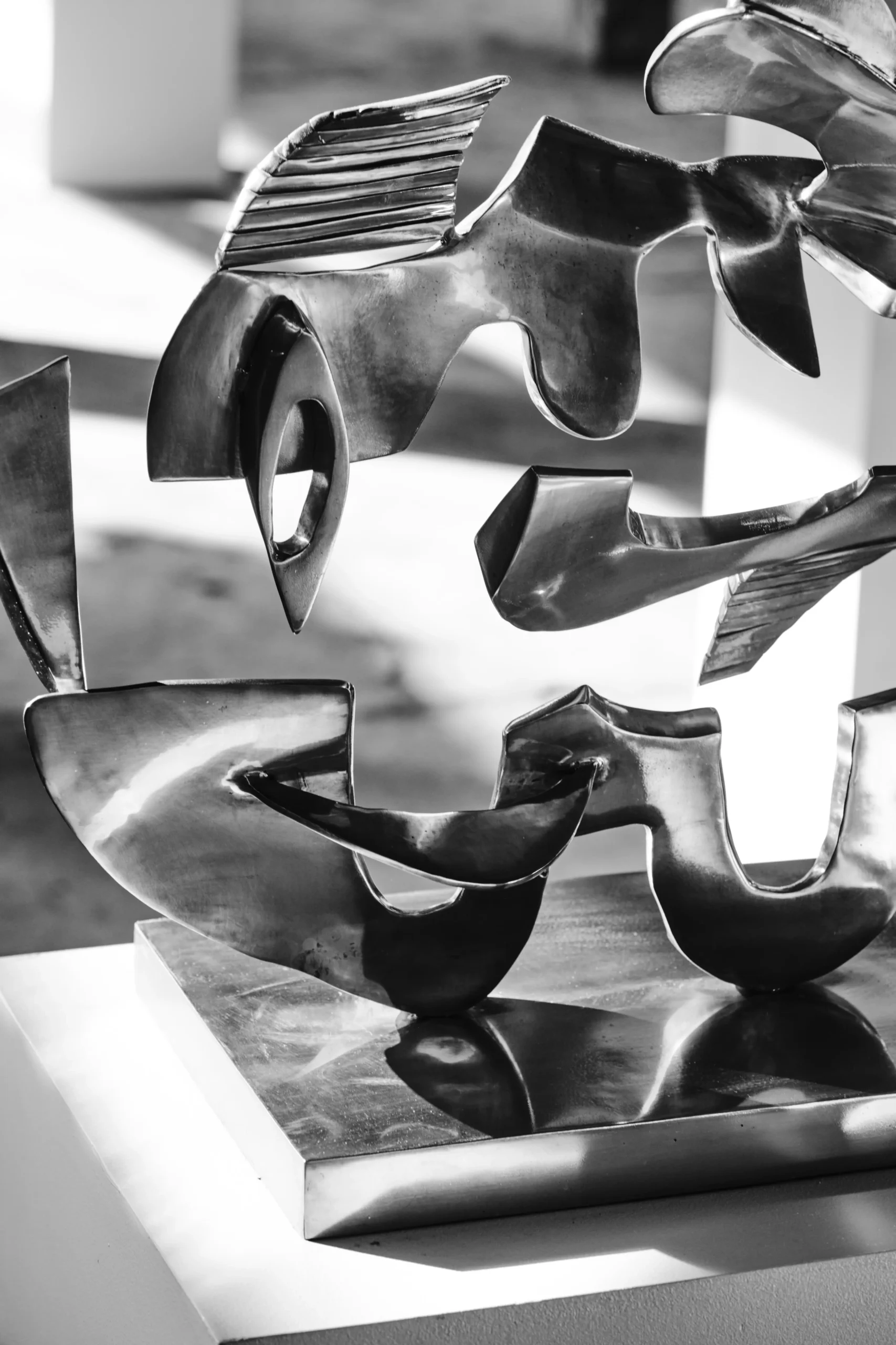 Abstract black-and-white metal sculpture of a bird in flight on a pedestal, with flowing, curved shapes and a glossy surface.  Anton V. Quisumbing, Sculpture, Pasulong